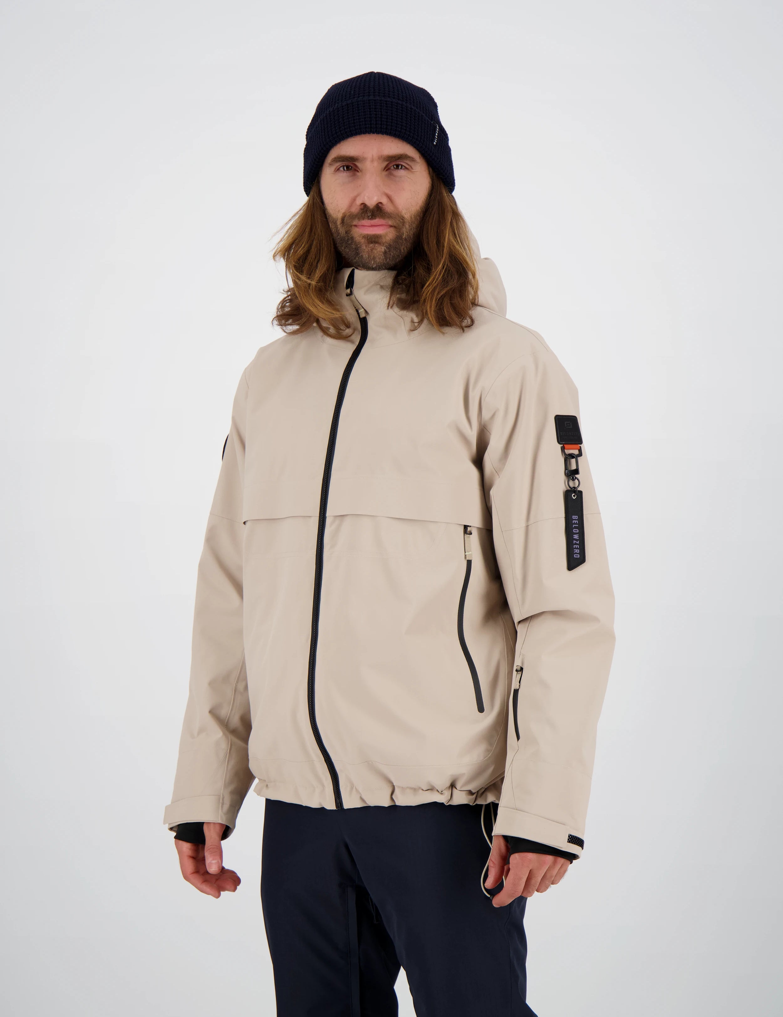 Funktionale Belowzero Herren-Skijacke in Beige mit Kapuze, schwarzen Kontrast-Reissverschlüssen, Ärmeltasche und markantem Oberarm-Tag.