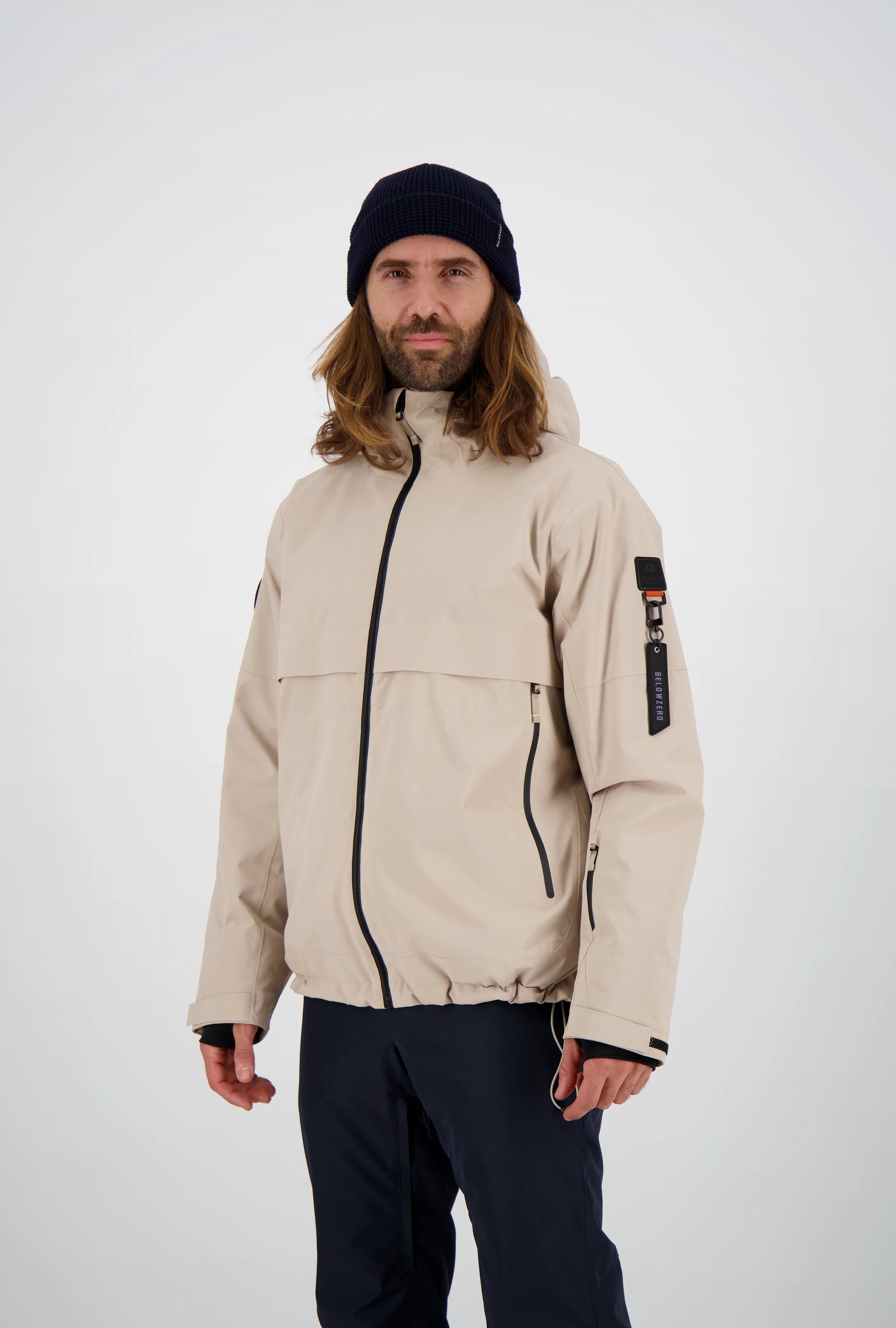 Funktionale Belowzero Herren-Skijacke in Beige mit Kapuze, schwarzen Kontrast-Reissverschlüssen, Ärmeltasche und markantem Oberarm-Tag.