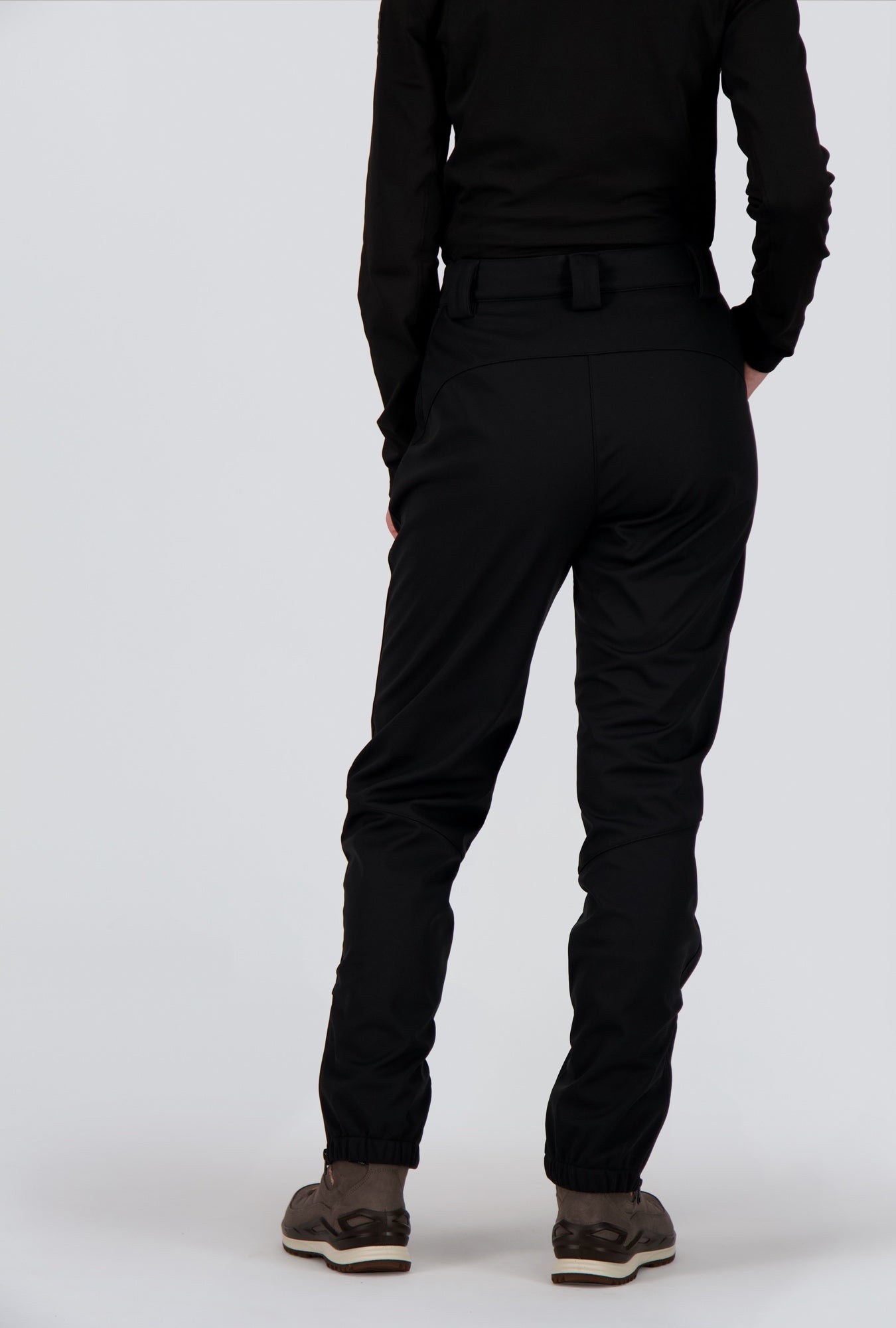 Rückseite einer Dame welche eine schwarze Softshellhose von Belowzero trägt.