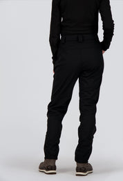 Rückseite einer Dame welche eine schwarze Softshellhose von Belowzero trägt.