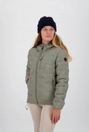 Gesteppte salbeigrüne grüne Damen-Outdoorjacke von Belowzero mit Kapuze, Reissverschlusstaschen und Logo-Badge am Ärmel, getragen mit beiger Funktionshose und dunkelblauer Strickmütze.