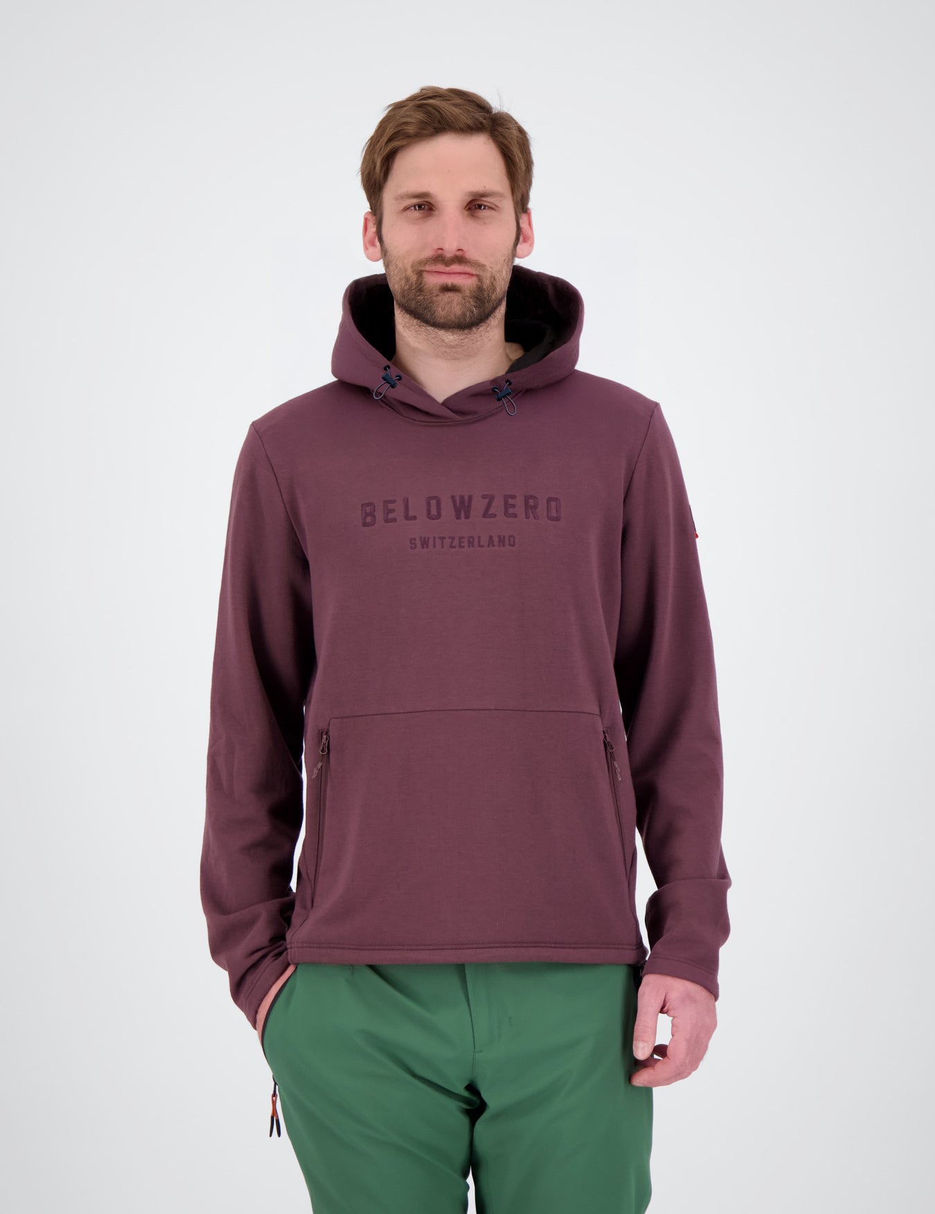 Frontansicht des mulled wine rotem bordeaux Herren Tech Hoodie Brig 
Bordeauxfarbener Herren-Fleece-Hoodie von Belowzero mit Kapuzenkordelzug, Logo-Stickerei auf der Brust und Kängurutasche mit Reißverschlüssen, kombiniert mit einer grünen Skihose bzw. Outdoorhose.
