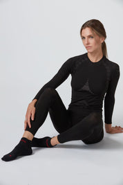 Frontansicht einer schwarzen funktionellen Warm Damen Baselayer Long Pant sitzend von Belowzero