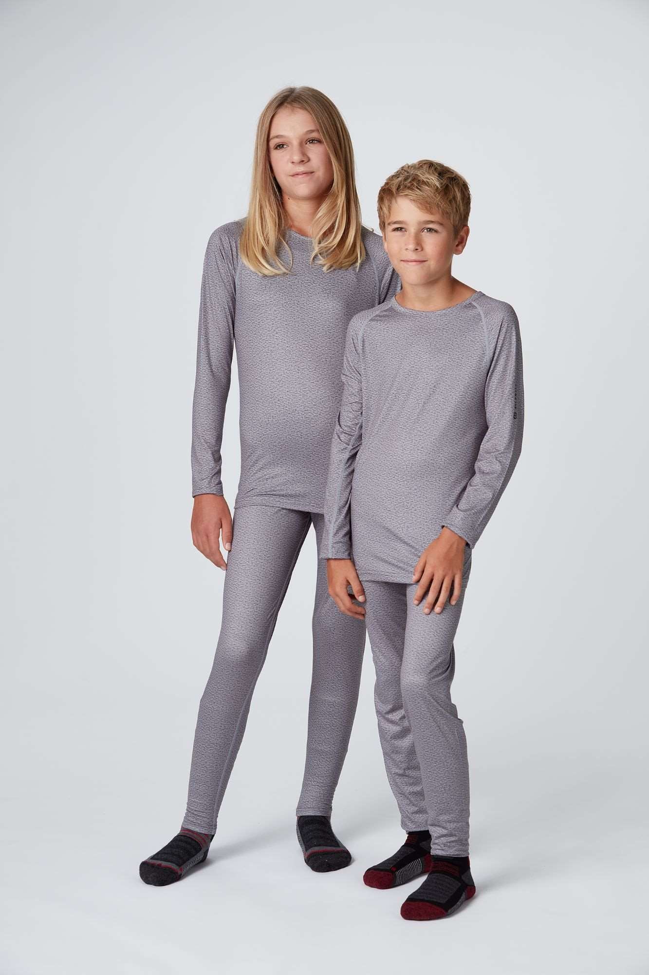 Frontansicht eines Mädchen und Jungen welche ein graues Longsleeve und Long Pants Baselayer Set Medium Light in grau tragen von Belowzero