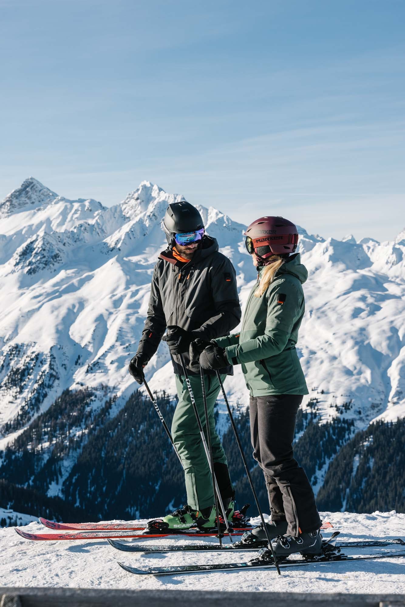 Ein Herr und eine Dame auf der Skipiste mit Belowzerobekleidung