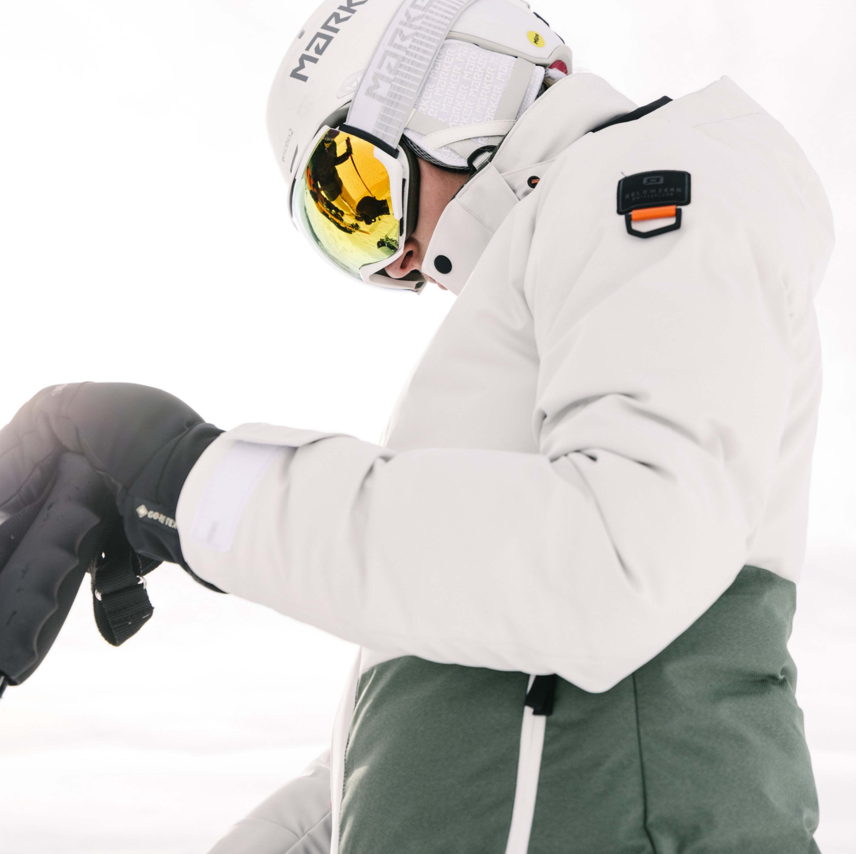 Eine Dame mit einer weissen Belowzero Skijacke im Schnee