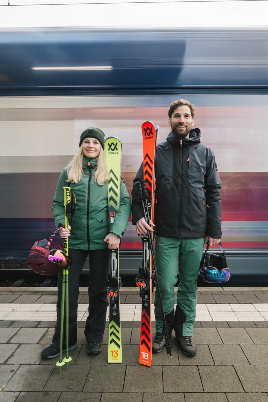 Eine Dame und ein Herr in Belowzero Bekleidung vor dem Zug