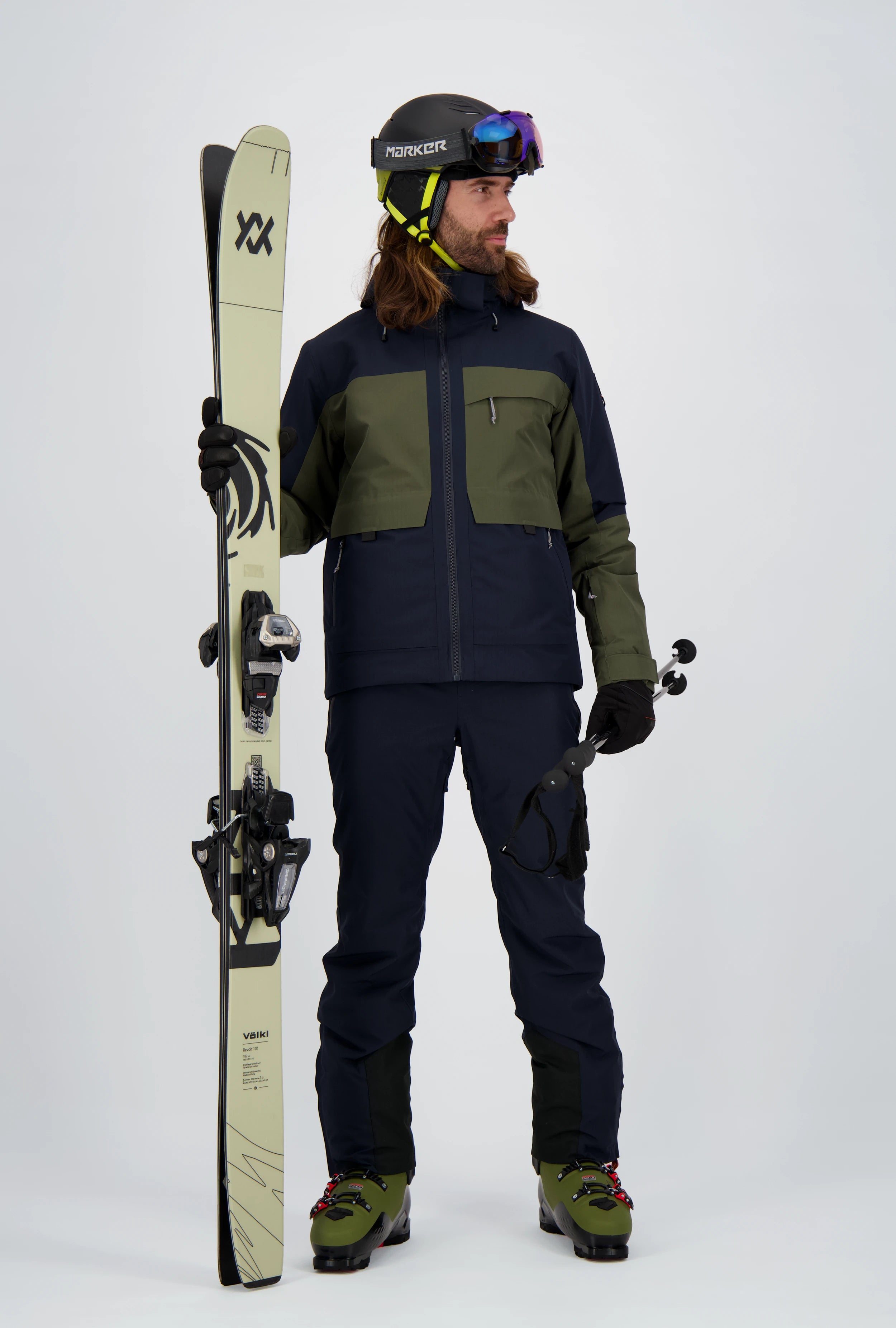 Ein Herrenmodel trägt die Leysin Jacke / Skijacke von Belowzero in navy/grün. Auf dem Bild ist die Ganzkörperansicht zu sehen.
