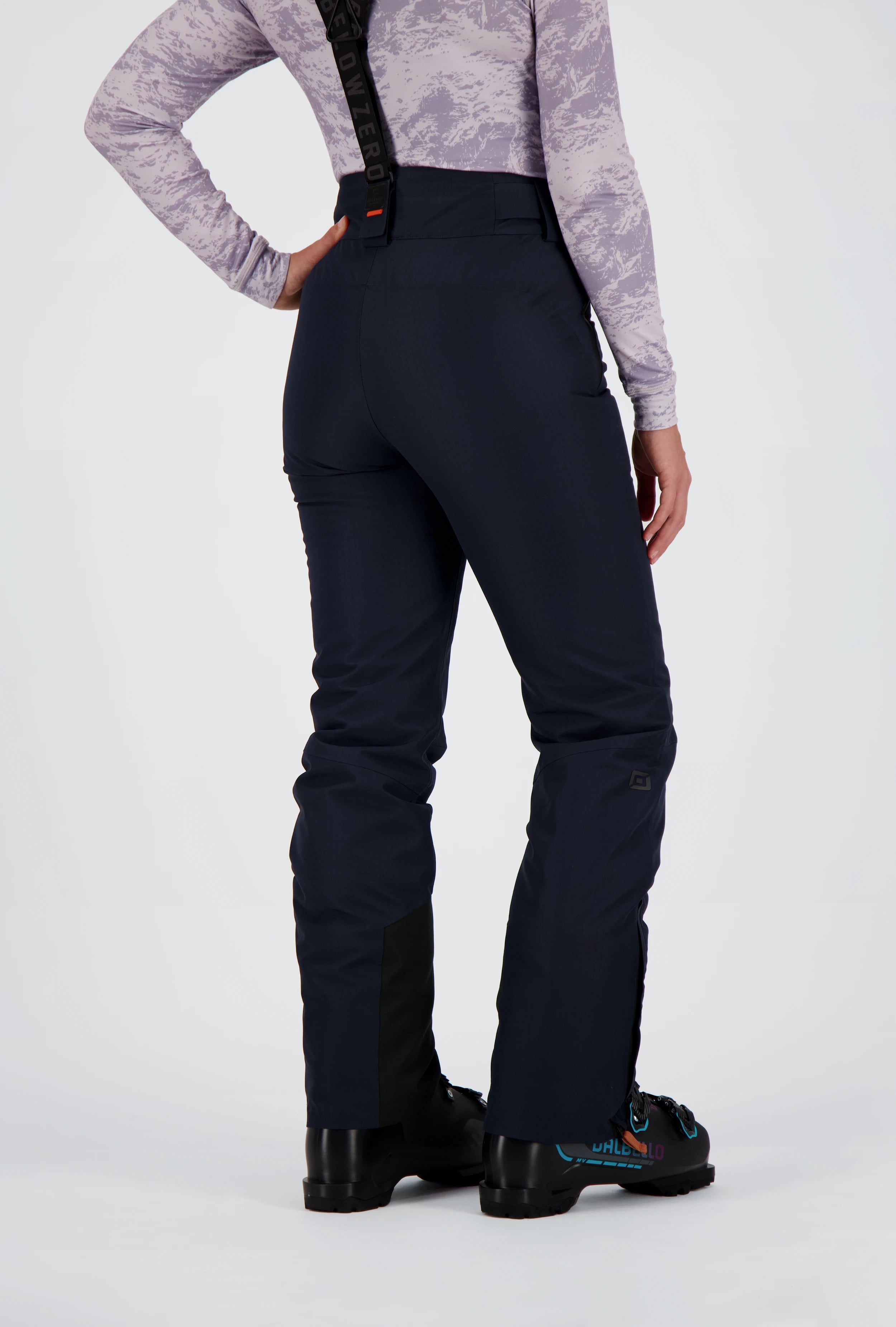 Ein Damenmodel trägt die Realp Skihose in blau von Belowzero. Auf dem Bild ist die Rückenansicht zu sehen.