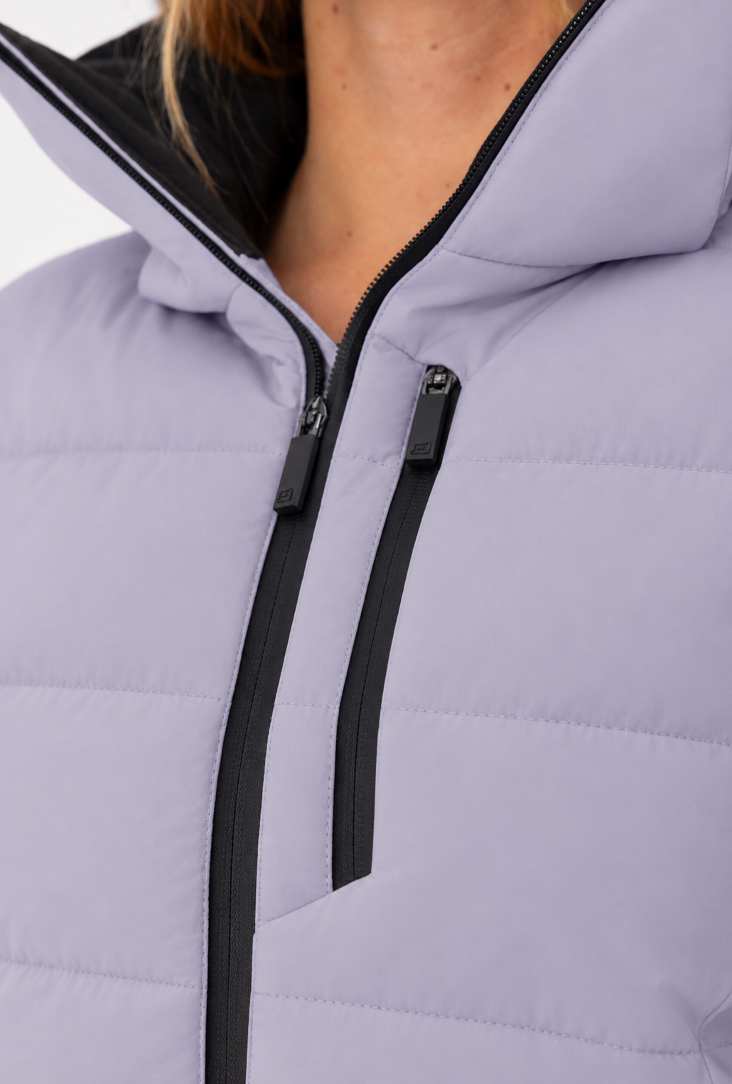 Detailansicht der Belowzero Damen-Skijacke in Flieder mit hochschliessendem Kragen, wasserabweisend getapter Brusttasche und Front-Reissverschluss.