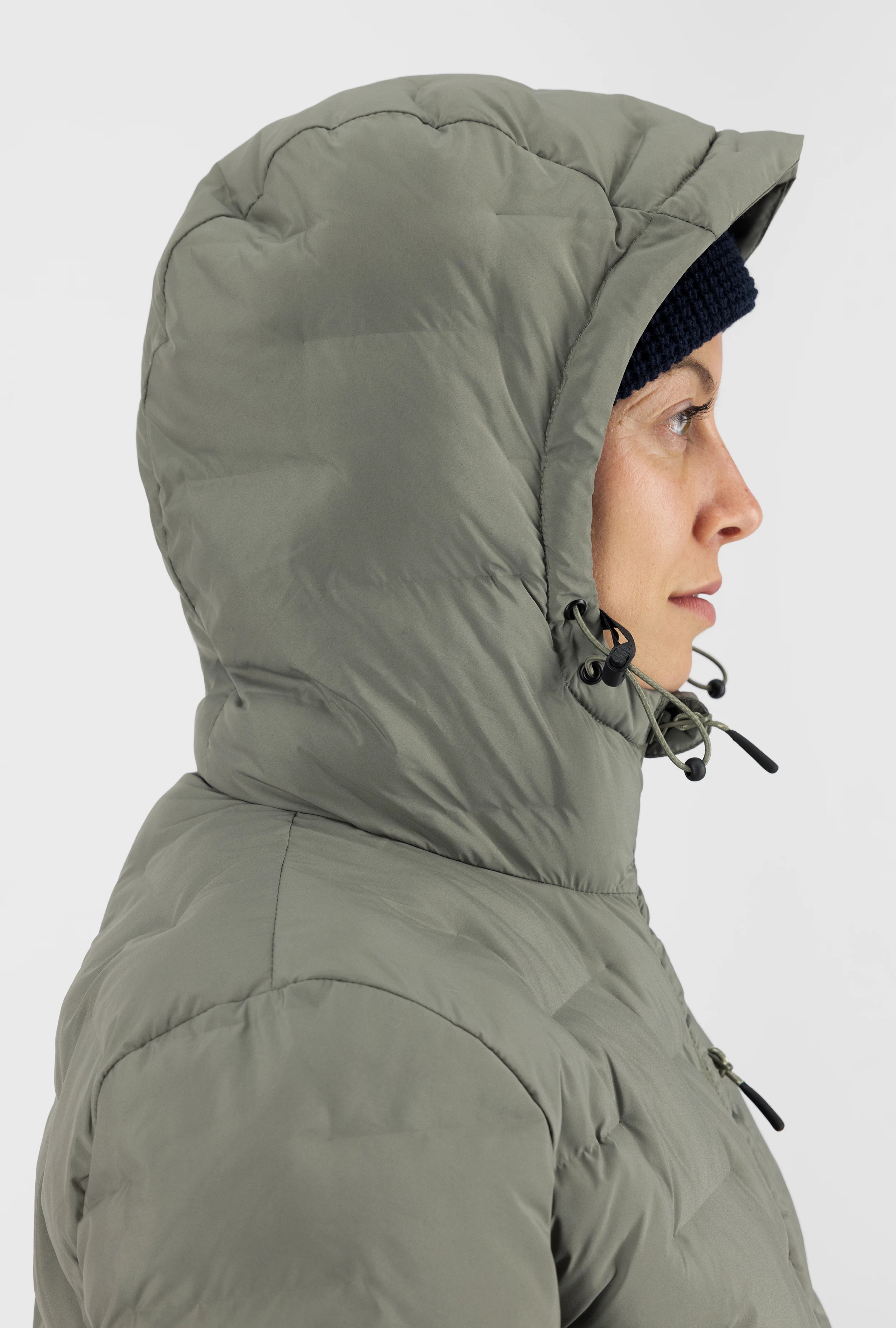 Seitenansicht einer olivgrünen Belowzero Damen Steppjacke mit aufgesetzter, verstellbarer Kapuze und Kordelzug für optimalen Wind- und Kälteschutz.
