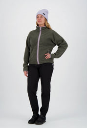 Frau mit fliederfarbener Beanie-Mütze trägt eine dunkelgrüne Belowzero Teddyfleece-Jacke mit fliederfarbenem Reissverschluss, schwarze Outdoorhose und schwarze Sportschuhe.