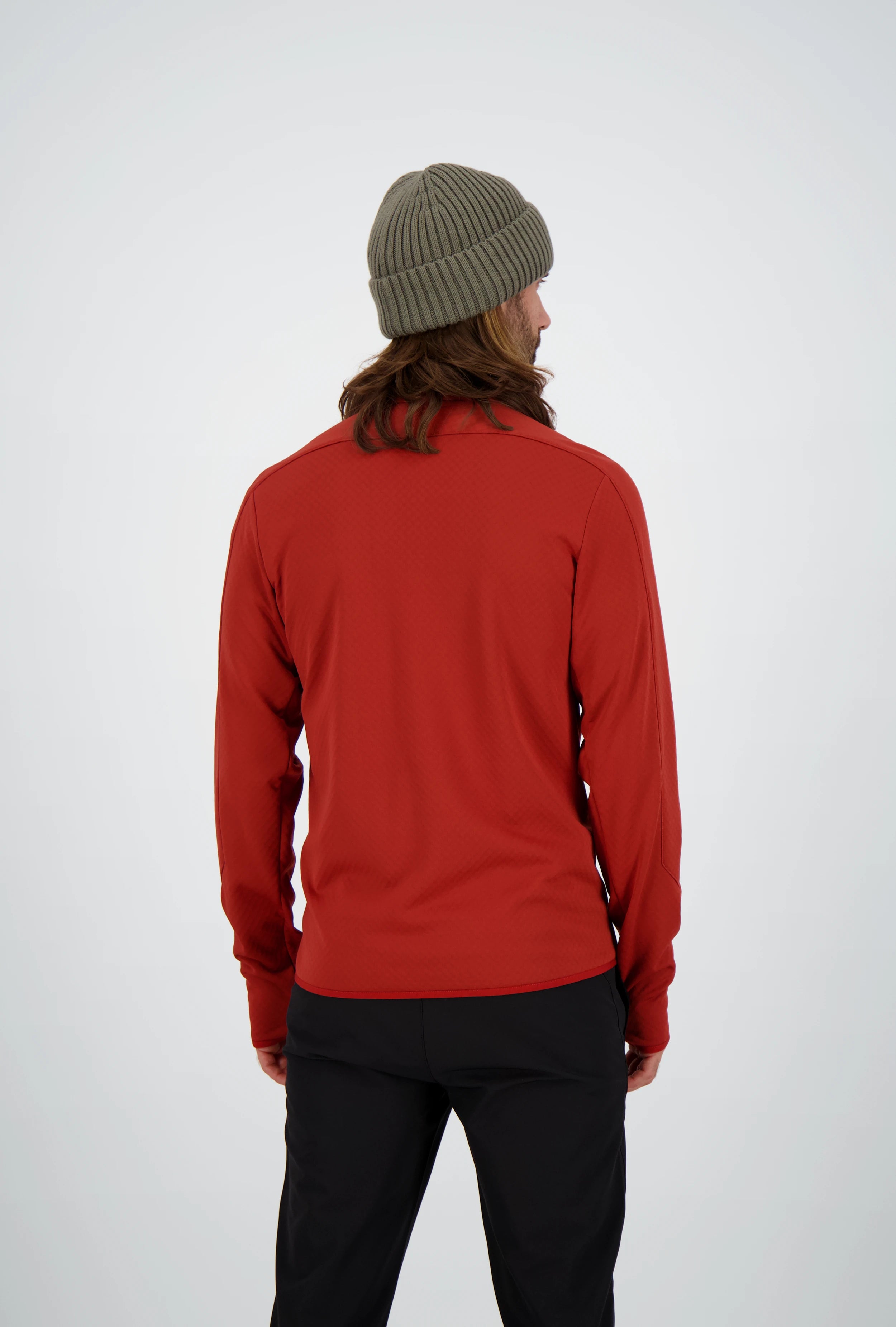 Rückenansicht eines Mannes mit langen Haaren und olivgrüner Beanie-Mütze in einer roten Belowzero Herren Fleecejacke  Midlayer und schwarzer Hose.