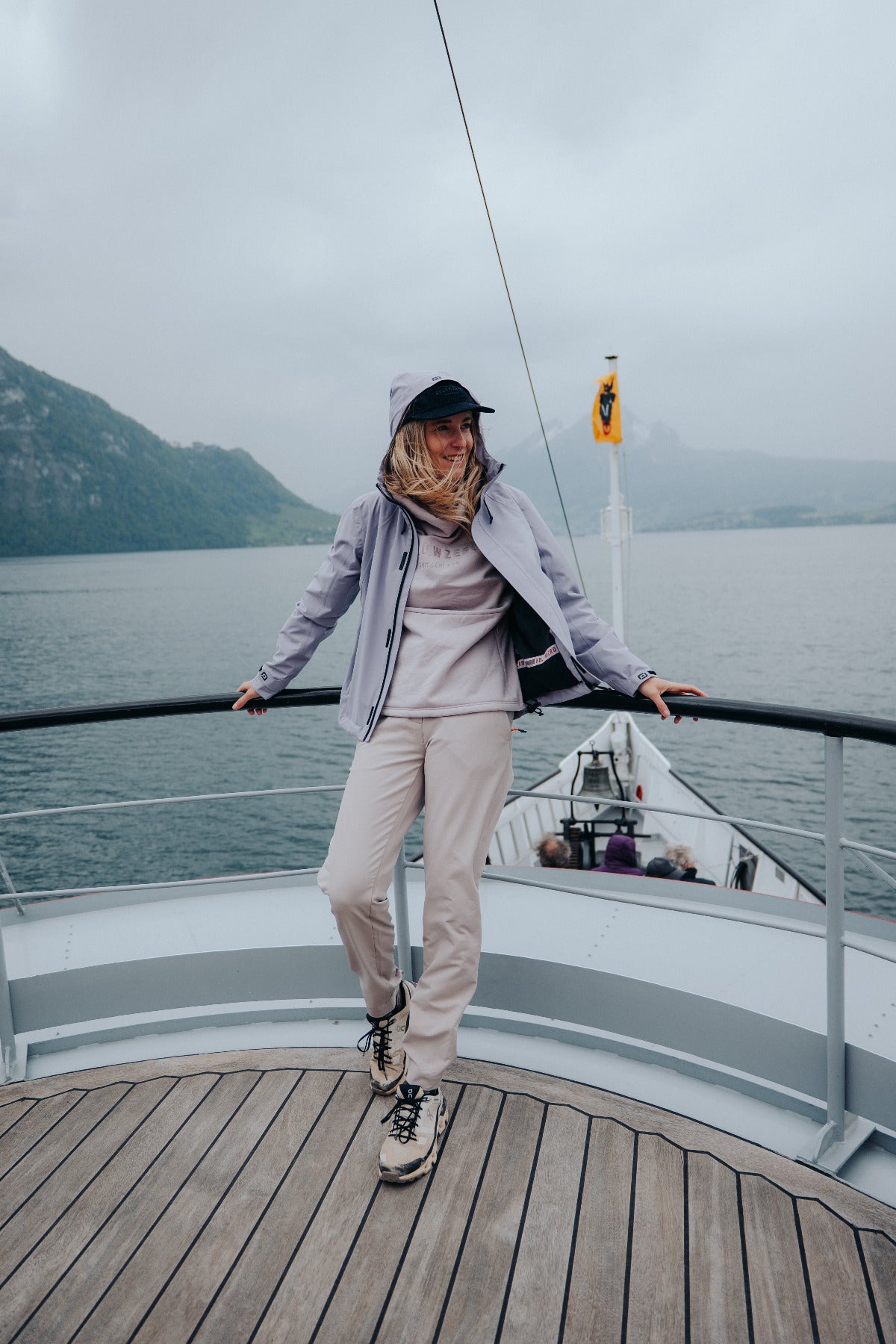 Frau in Belowzero Jacke auf dem Bootsdeck vor Bergkulisse